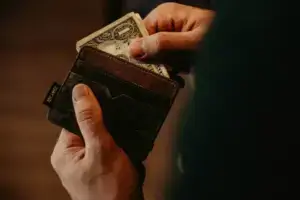 Persona guardando un billete de un dólar en la cartera