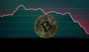 Moneda de Bitcoin frente a un gráfico de precios en caída
