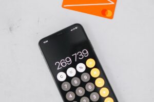 Calculadora en un smartphone junto a una tarjeta de crédito naranja