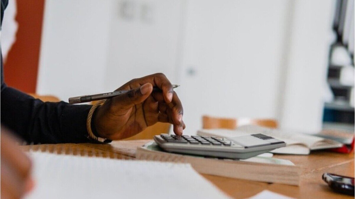 Mano usando una calculadora sobre una mesa mientras revisa su presupuesto