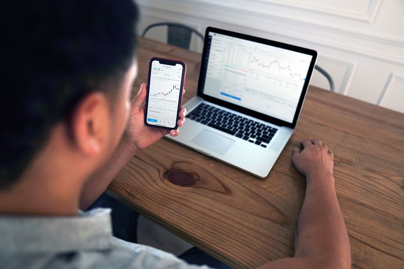 Invertir con poco dinero: hombre mirando gráficos en su teléfono y computadora