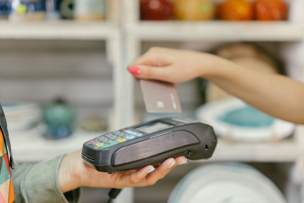 Tarjeta con reembolso: mano acercando una tarjeta a una terminal de pago